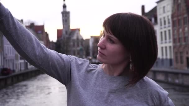 Девушка турист делает селфи на смартфоне на закате в Брюгге Бельгия. замедленное движение — стоковое видео