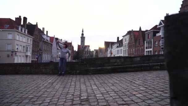 Bruges Şehir Belçika bir arka plan üzerinde bir akıllı telefon üzerinde selfi kız turist yapar — Stok video