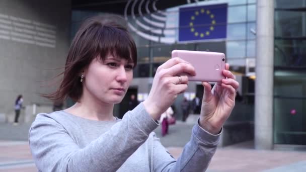 Vrouw toeristische neemt pictureson op smartphone in de buurt van het Europees Parlement in Brussel. België. — Stockvideo