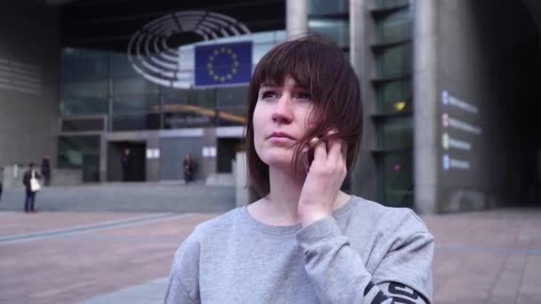 Dame is lopend en pratend aan de telefoon in de buurt van het Europees Parlement in Brussel. België. Slow motion. — Stockvideo