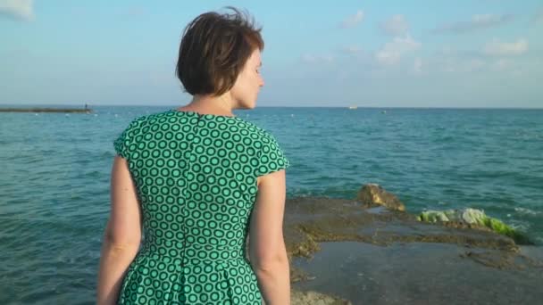Женщина в платье ходит по морским скалам во время высоких волн. Slow Motion — стоковое видео