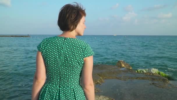 Femme en robe marcheurs sur les rochers de mer lors de hautes vagues. Mouvement lent — Video