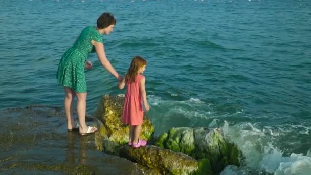 Frau mit Mädchen auf Felsen in Wellen. Zeitlupe — Stockvideo