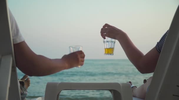 Парочка на полях, звенящая с напитками на пляже — стоковое видео