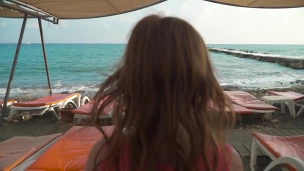 Menina andando na praia com espreguiçadeiras — Vídeo de Stock
