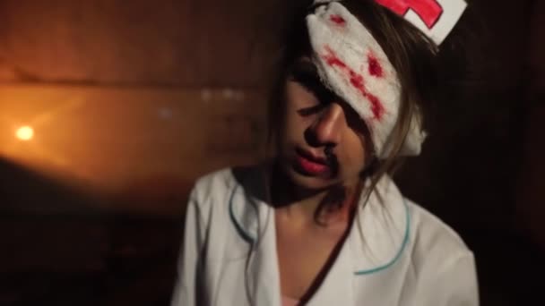 Monstruoso médico manchado de sangre y con vendaje en un ojo, sostiene la jeringa con sangre — Vídeo de stock