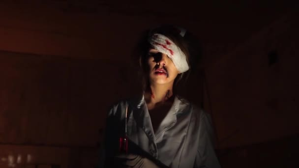 Чудовищный доктор с пятнами крови и повязкой на одном глазу, держит шприц с кровью — стоковое видео