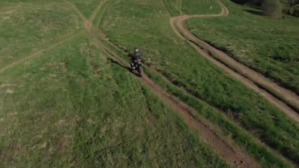 Motocicleta enduro paseos en carretera arenosa en campo verde, tiro aéreo — Vídeo de stock