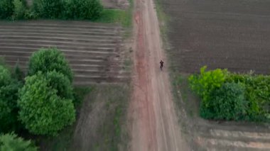 Havadan çekim Genç adam bisiklet tarım arazileri ile kırsal Road üzerinde Bisiklete binme