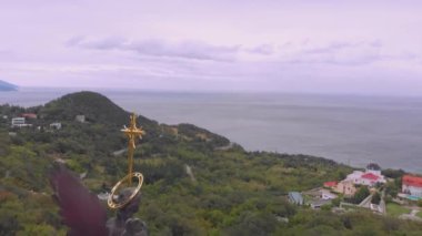 kuş gözü uçuş yeşil ormanlar ile engebeli sahil üzerinde çapraz kilise ve küçük kasaba bulutlu gökyüzü altında gri deniz tarafından geçmiş