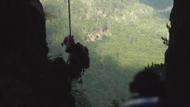 Alpinista silhueta descendo a rocha por corda no fundo do céu — Vídeo de Stock