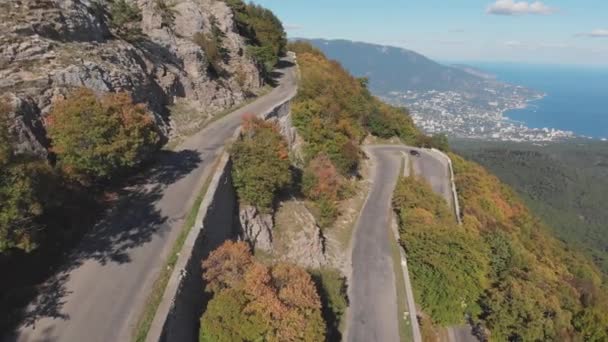 Tiro aéreo: estrada de montanha e vista da cidade costeira do mar no dia ensolarado de verão . — Vídeo de Stock