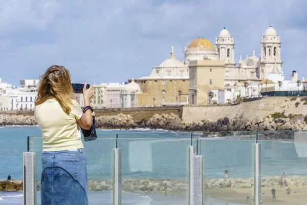 Bir kadın, güneşli bir günde deniz kıyısından gelen görkemli Cadiz Katedrali 'ni düşünüyor.