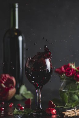 Bir bardak kırmızı şarap. Romantik akşam bir kadeh şarap Sevgililer günü için ile. Tatil kompozisyon bir siyah tablo ve arka plan üzerinde. İçki sıçrama