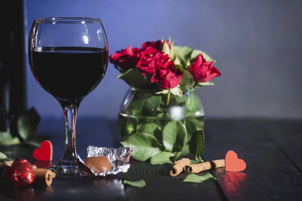 Red wine in a glass. Romantic evening with a glass of wine to Valentine\'s day.Holiday composition on a black table  and  background.