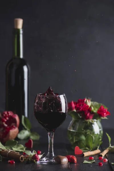Red wine in a glass. Romantic evening with a glass of wine to Valentine\'s day.Holiday composition on a black table  and  background. Splash of drink