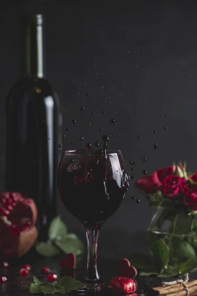 Red wine in a glass. Romantic evening with a glass of wine to Valentine\'s day.Holiday composition on a black table  and  background. Splash of drink