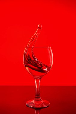 Bir bardak şarap. Kırmızı bir arka plan üzerinde cam içmek.