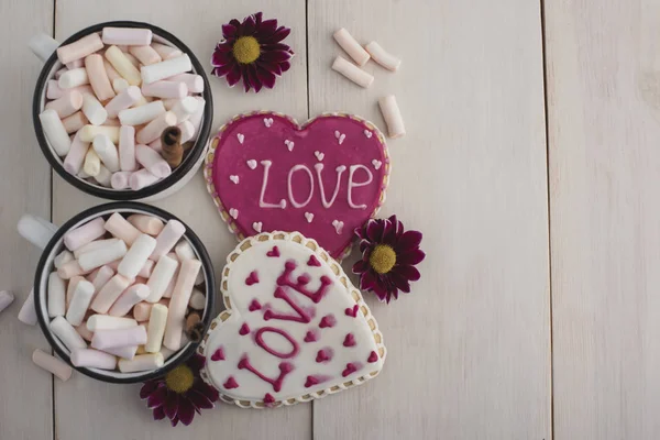Romantic breakfast for valentine day. A delicious drink of marshmallows and heart-shaped cookies. Breakfast for lovers on a white  wooden table