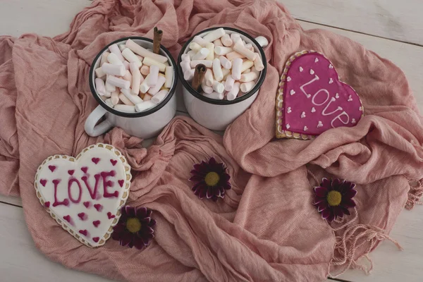 Romantic breakfast for valentine day. A delicious drink of marshmallows and heart-shaped cookies. Breakfast for lovers on pink textile