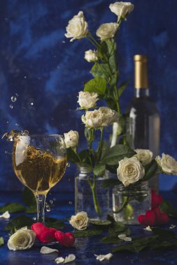 Sevgililer günü. Beyaz şarap. Romantik akşam. Şarap, bir demet beyaz gül ve mavi bir arka plan üzerinde kırmızı kalpler. Tatil severler. İki kişi için lezzetli bir alkollü içecek. Resmi fotoğraf.