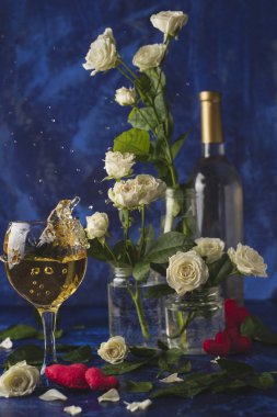 Sevgililer günü. Beyaz şarap. Romantik akşam. Şarap, bir demet beyaz gül ve mavi bir arka plan üzerinde kırmızı kalpler. Tatil severler. İki kişi için lezzetli bir alkollü içecek. Resmi fotoğraf.
