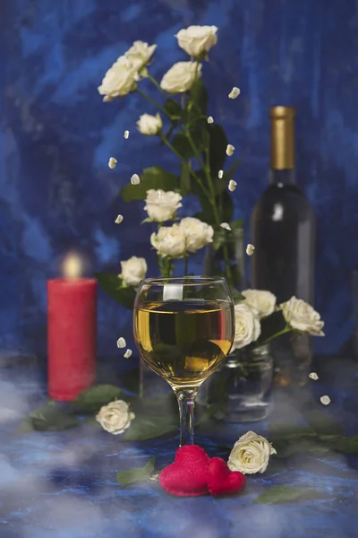 Valentine day. White wine. Romantic evening. Wine, a bunch of white roses and red hearts with smoke on a blue background. Holiday of lovers. A delicious alcoholic drink for two people.Picture magic