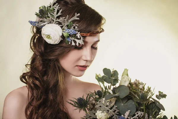 Spring, summer fashion photo shoot at the studio. Beautiful girl with flowers in the background.Tenderness, beauty on the pictures.Beautiful model.Spring composition of natural flowers.Portrait