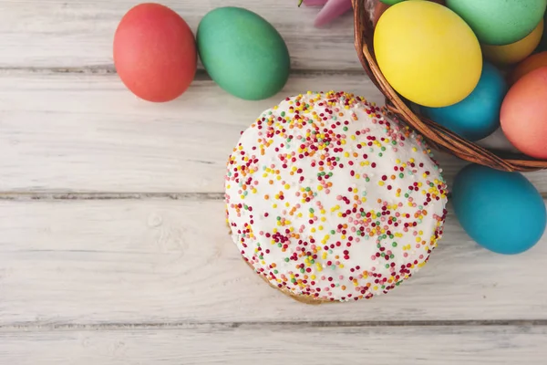 Colorful easter eggs,cake on wooden texture background.On a white wood table,colored eggs,bread.Happy religious day,traditional for people. Top view.Copy space.