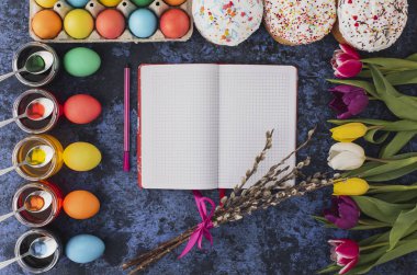 Easter.Notebook yazma, renkli yumurta, Bahar laleler, mavi arka plan üzerinde Pastalar. Tatil ayarla. Dini günün kutlu olsun insanlar için geleneksel. Üstten Görünüm. Uzay kopyalayın. Kavramı