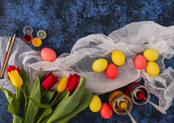 Easter blue background with red and yellow eggs on the fabric. Spring  colored flowers tulips.Holiday set.