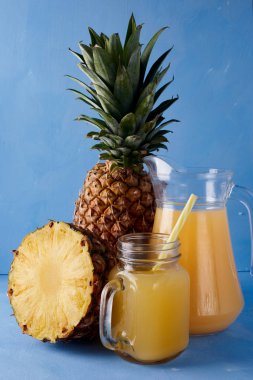 Ananas suyu ve taze tropikal meyve mavi bir arka plan üzerinde. Tatlı yaz içeceği bileşimi. 