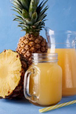 Ananas suyu ve taze tropikal meyve mavi bir arka plan üzerinde. Tatlı yaz içeceği bileşimi. 