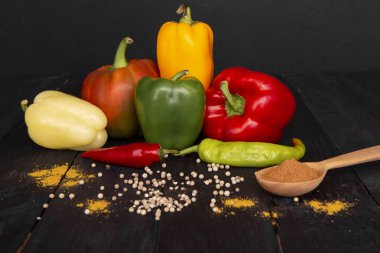 Tahta siyah bir masa üzerinde taze biber bir kompozisyon. Koyu renkli bir arka plan üzerinde lezzetli renkli sebzeler. 