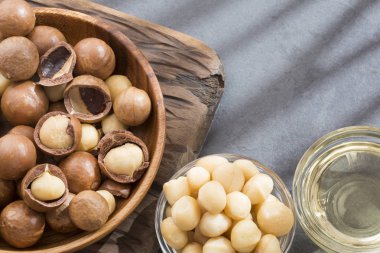 Ahşap tahta üzerinde üstten görünüm Macadamia fıstığı kabuklu ve unshelled ve doğal macadamia yağ. Sağlıklı ürün.