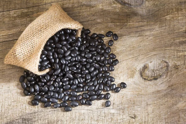 木製の背景に黒い豆を生 — ストック写真