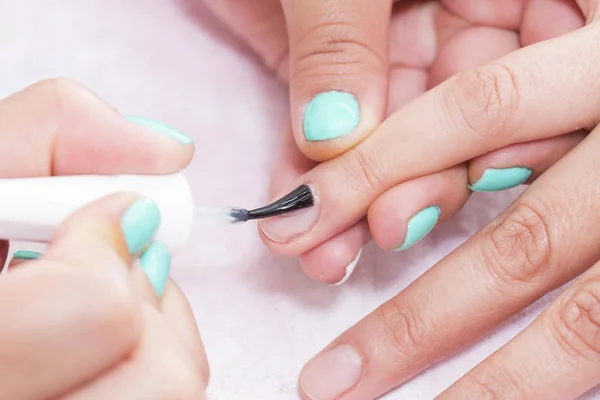 Nail Care And Manicure. Closeup Of Beautiful Female Hands Applying Transparent Nail Polish On Healthy Natural Woman\'s Nails In Beauty Salon.