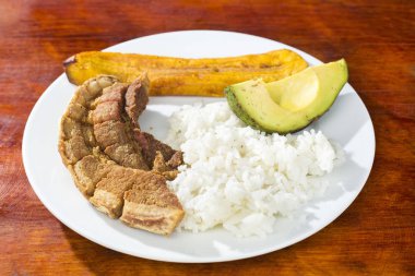 Pork rind, rice, fried banana and avocado - Typical Colombian dish clipart