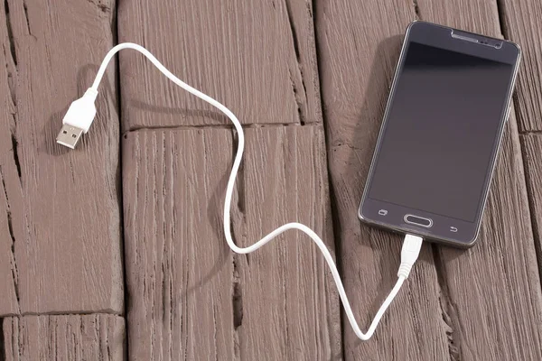 USB kablosu - ahşap arka plan ile telefon