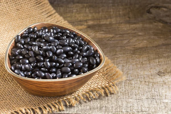 Ahşap arka plan üzerinde ham siyah fasulye