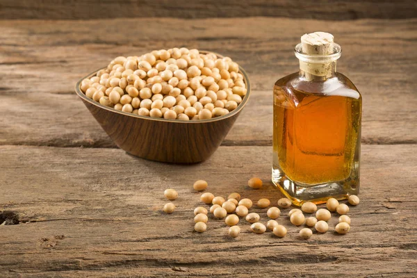 Oil and soybeans - Glycine max. Wooden background