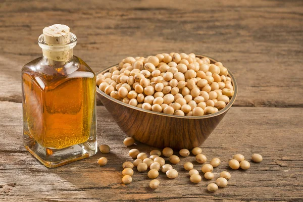 Oil and soybeans - Glycine max. Wooden background