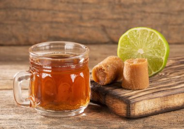 Fresh homemade Aguapanela, Agua de Panela or Aguadulce, a popular Latin American sweet drink made of panela unrefined whole cane sugar boiled in water, served warm or cold with lime. clipart
