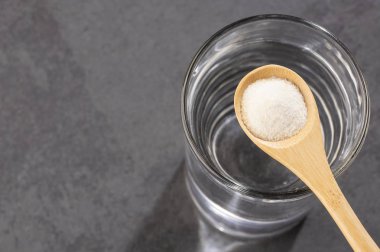 Kaşıkta toz kolajen protein var. Bir bardak su.