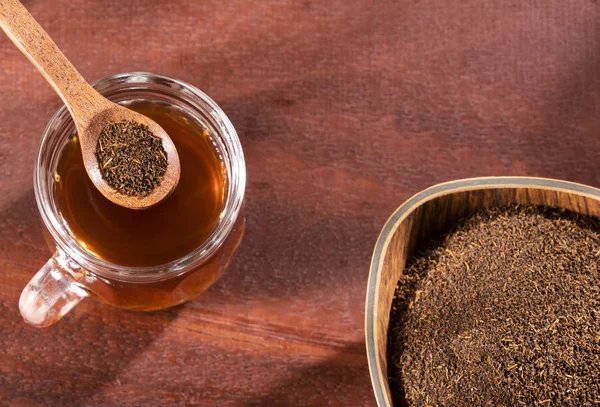 Schwarzer Tee in einer Tasse und getrocknete und gepuderte Blätter - Camellia sinensis — Stockfoto
