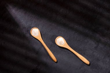 İki tahta kaşıkta hidrolize kolajen protein tozu.