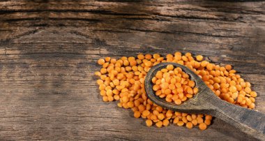 Kırsal ahşap arka planda pişmemiş portakallı mercimek.