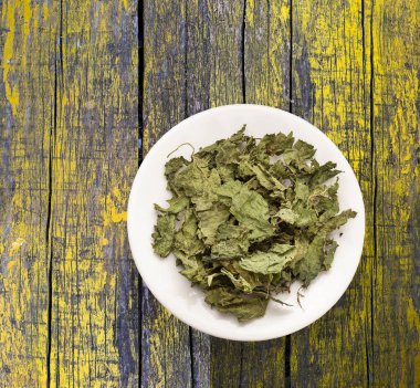 Kurumuş, tıbbi ve kurutulmuş ısırgan otu yaprakları bir kasede.