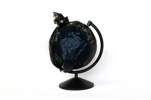 A globe of the earth in a plastic black bag like trash over white background, the concept of ecology problem and World Environment Day. Photo with message for social advertising, place for inscription