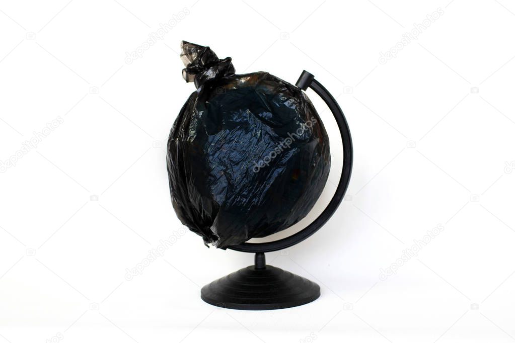 A globe of the earth in a plastic black bag like trash over white background, the concept of ecology problem and World Environment Day. Photo with message for social advertising, place for inscription